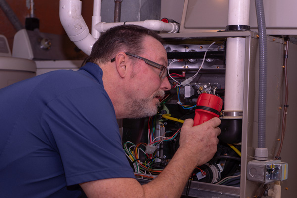HVAC technician attending to furnace depicting indoor CO cause