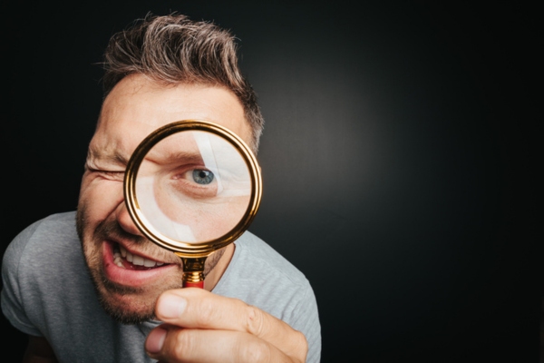man looking through magnifying glass depicting ways to find AC SEER rating