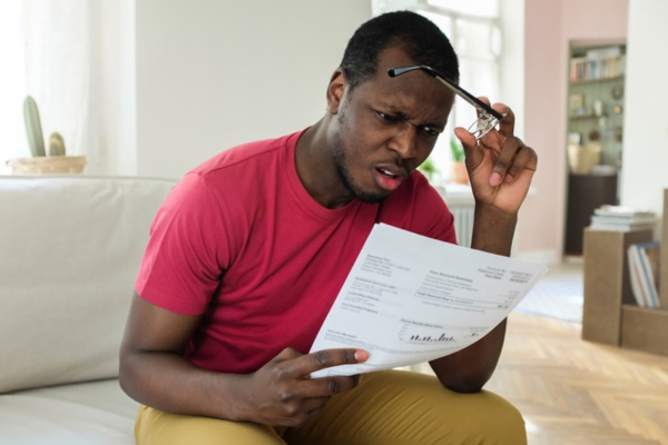 man looking surprised while reading high energy bill
