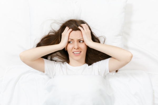 woman looking tired with hands on face and ears depicting noisy AC compressor