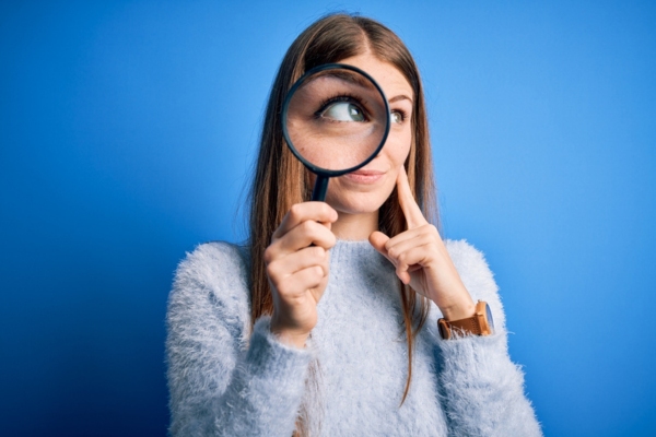 woman using magnifying glass depicting signs that heating oil filter needs to change