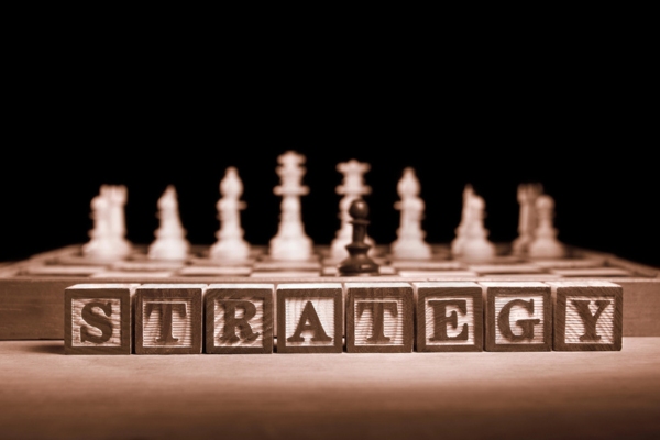 strategy spelled using letter cubes with chess pieces in the background depicting ways to reduce heating oil consumption