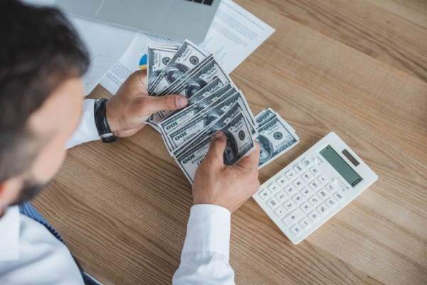 homeowner counting cash and computing expenses depicting controlling heating oil costs