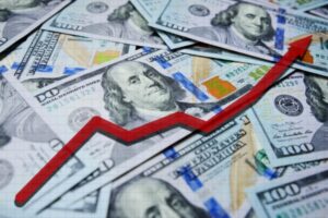 red arrow chart with 100 dollars as background depicting fluctuation of oil prices