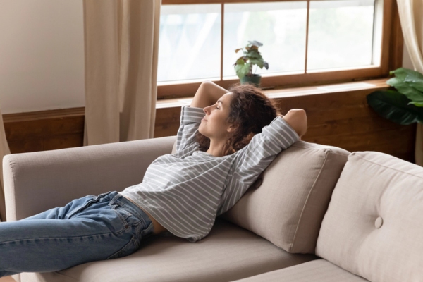 woman staying cozy and comfortable indoors lounging on the couch