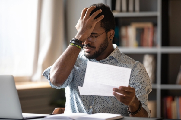 man holding up energy bill with another hand on forehead feeling stressed due to high energy bill