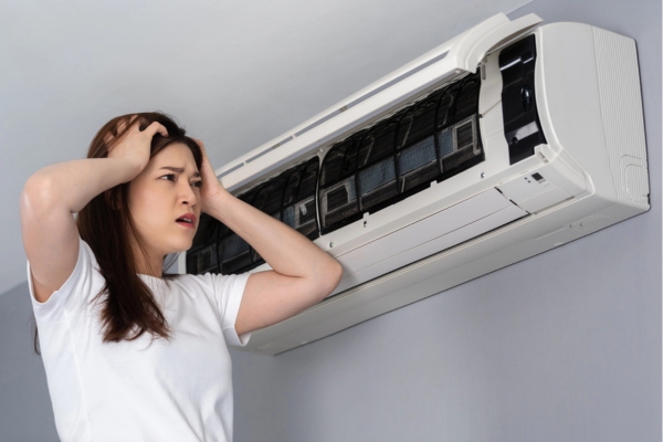 woman feeling stressed while checking ductless air conditioner