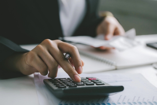 homeowner using a calculator depicting weighing the cost of Central vs. Ductless Cooling