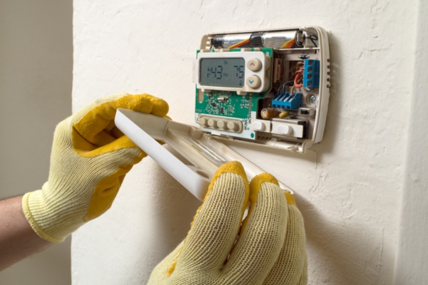 HVAC technician assessing home thermostat