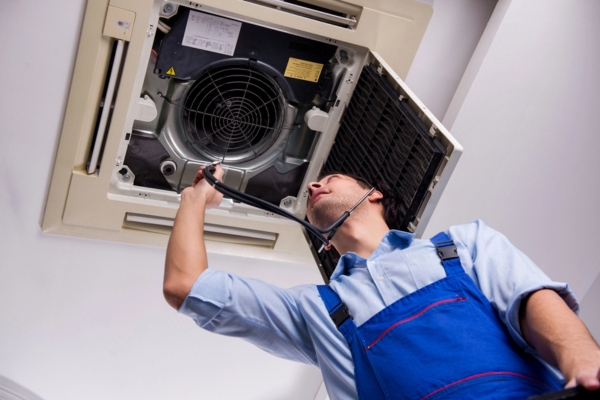 professional HVAC contractor listening to indoor HVAC unit