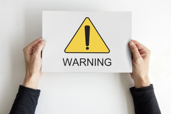warning sign on a paper held by a man's hand depicting heating oil tank sludge