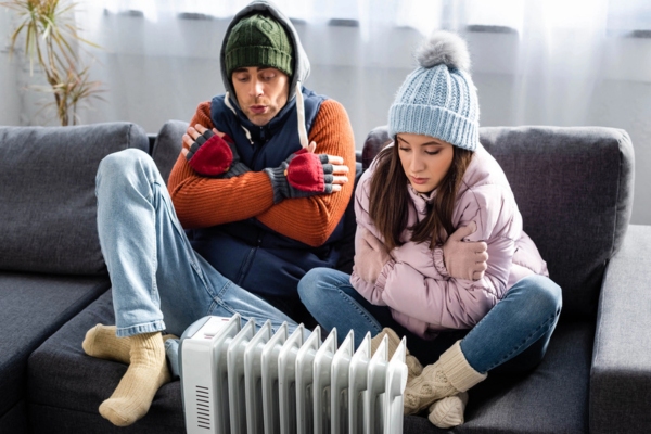 couple feeling cold in front of a space heater