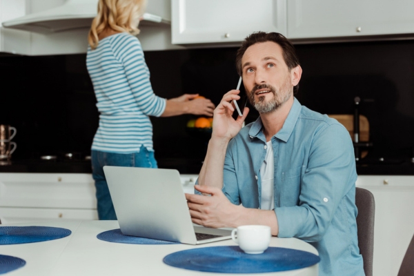 man talking on the phone with a laptop in front of him