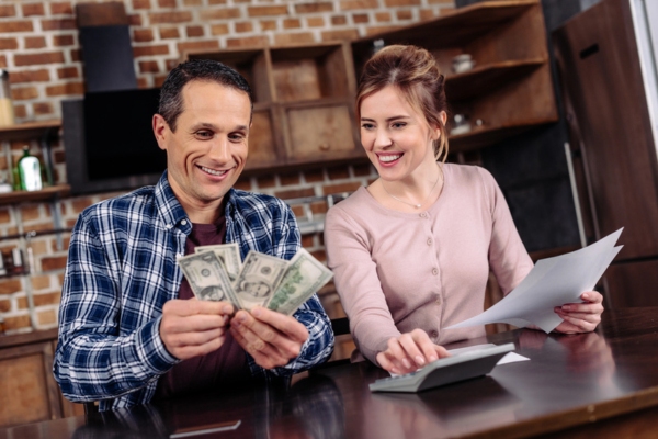 happy couple counting money together at home depicting savings from efficient heating oil use