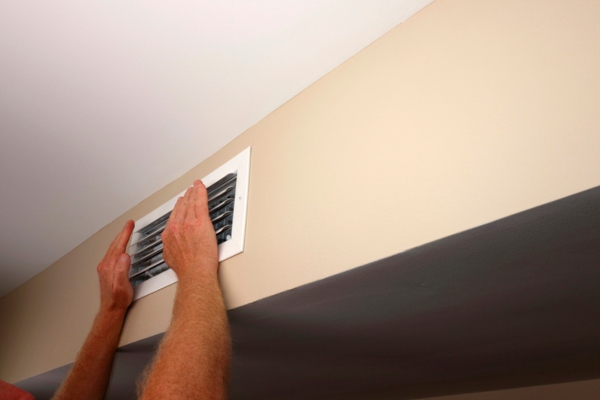 homeowner feeling air vent for air conditioner cool air