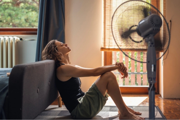 Young woman suffering from heat sitting at home on the floor due to reduced AC efficiency