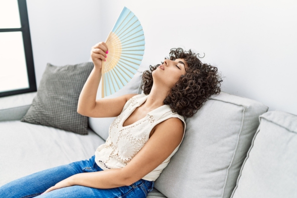 woman using hand fan at home due to HVA system breakdown
