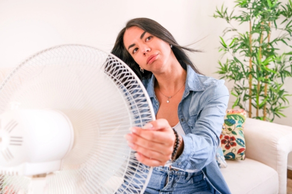 woman sitting in front of a fan due to AC blowing weak air